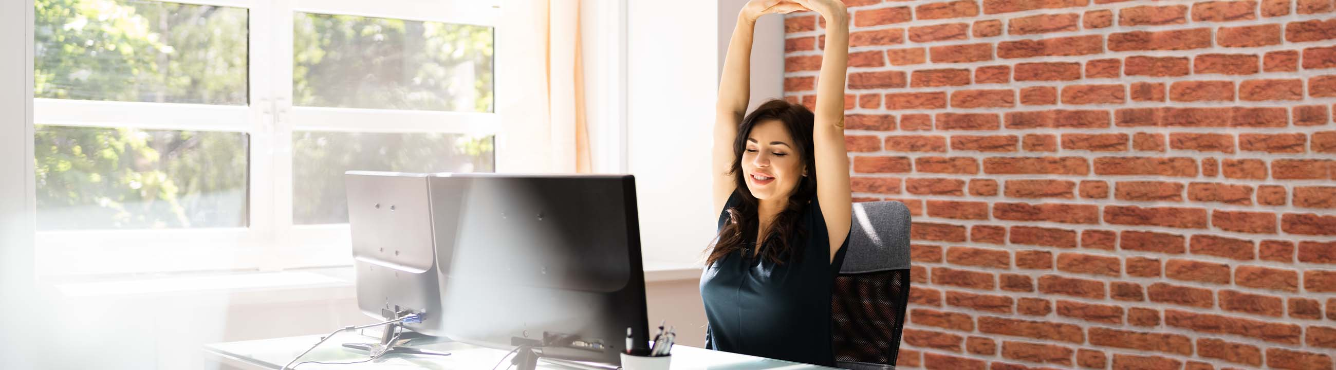 Woman sitting in an office stretching her arms